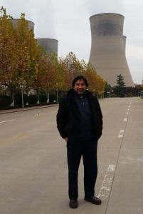 Author Carlos Romero standing in front of coal-fired power plant